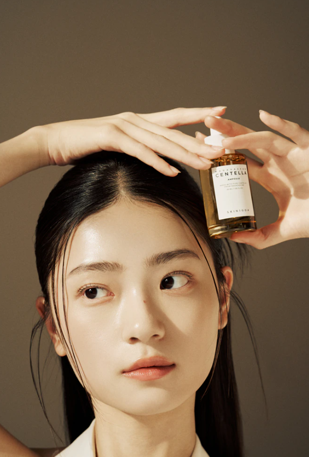 Modelo segura o SKIN1004 Madagascar Centella Ampoule junto à cabeça